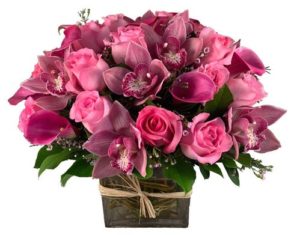 clustered arrangement of pink roses, pink cymbidium orchids, pink mini callas and pink filler in a square vase