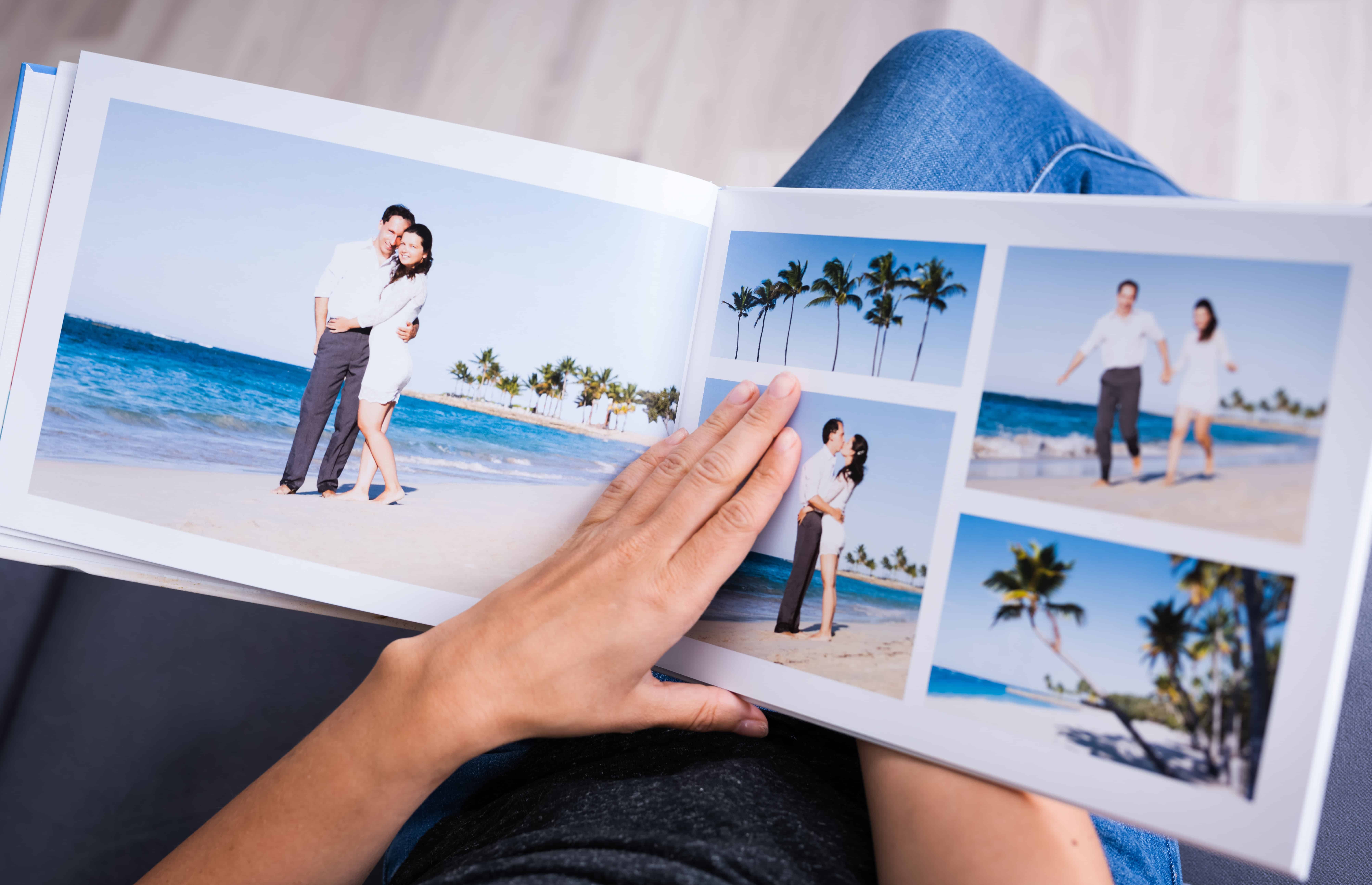 Open hard cover photo book opened to pages with pictures of couple on beach